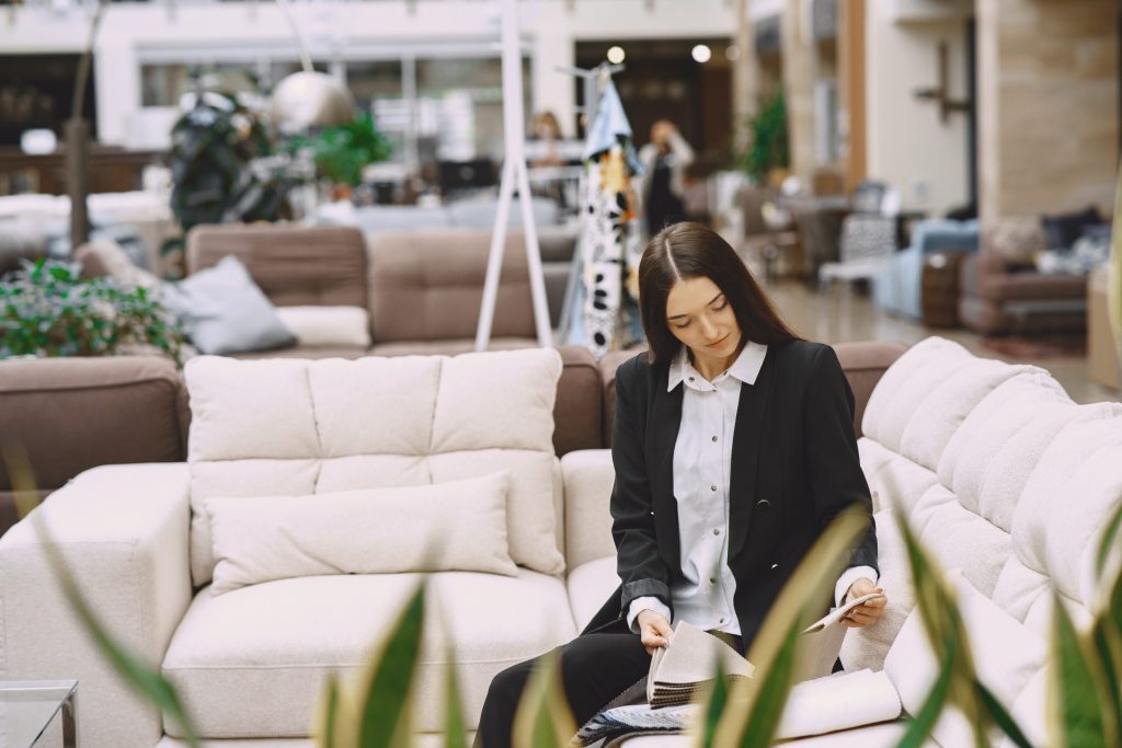Kvinna sitter i en ljus soffa och tittar på tygprover i en möbelbutik